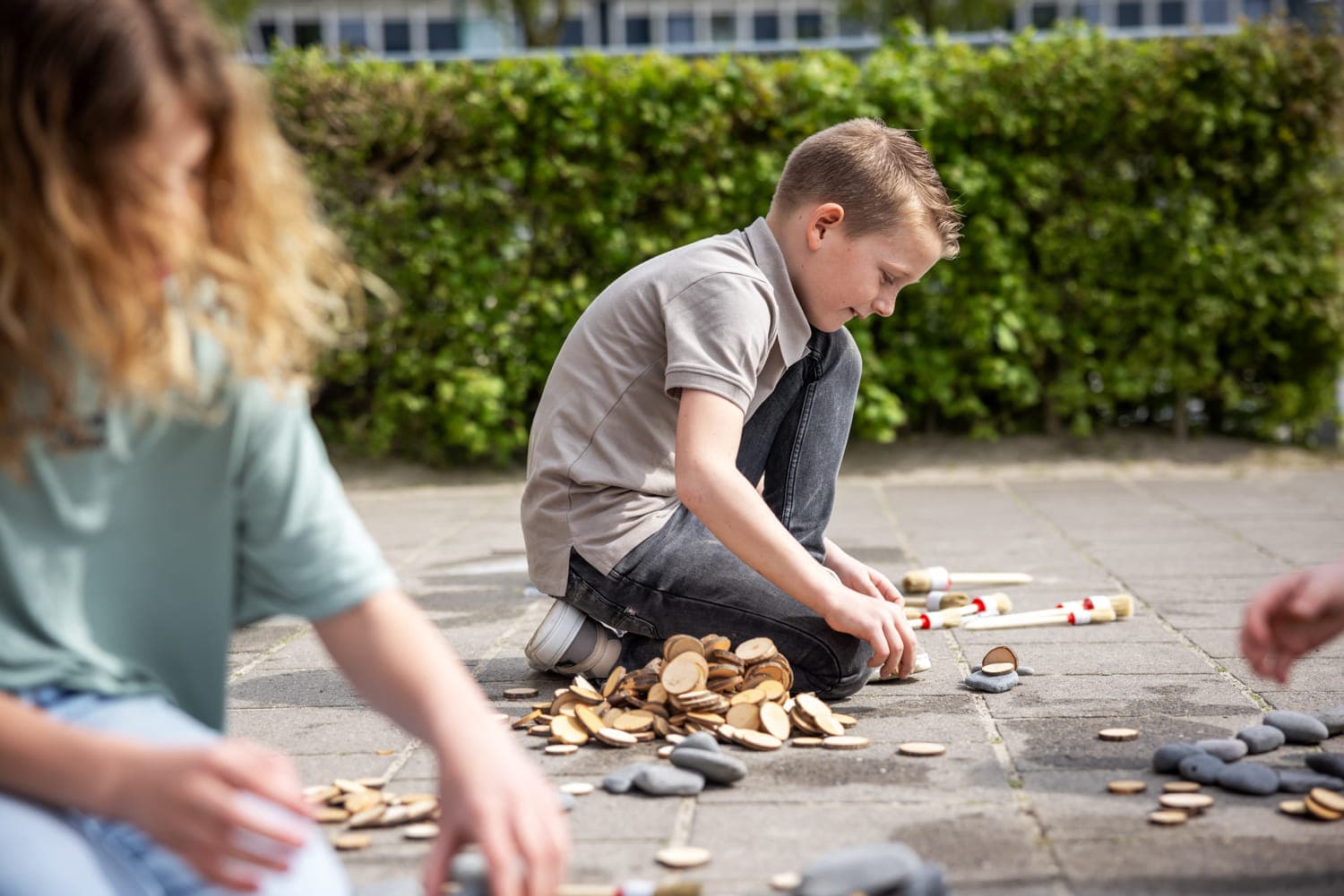 Kinderen spelen buiten op de grond bij kinderopvang Kind&co ludens
