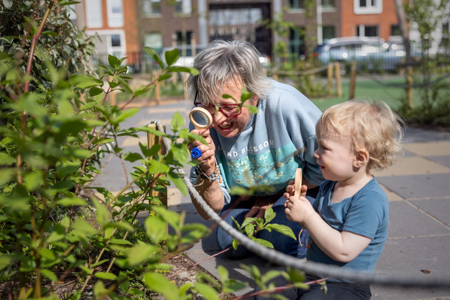 Pedagogisch medewerker en kind kijken samen door een loep naar blaadjes bij kinderopvang Kind&co ludens