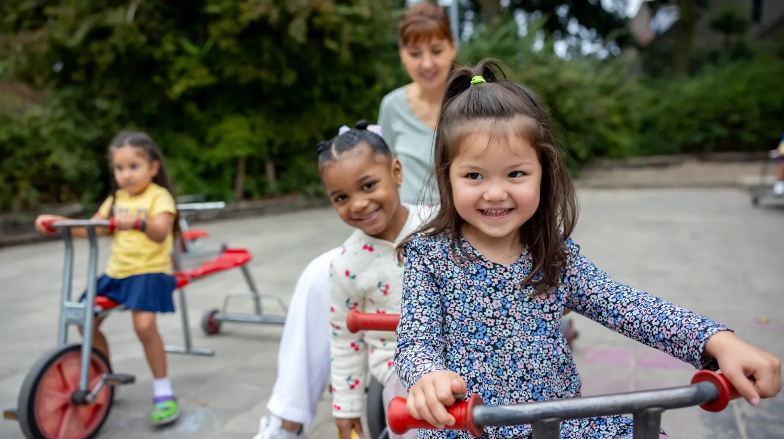 Kinderen spelen buiten met pedagogisch medewerker bij kinderopvang Kind&co ludens