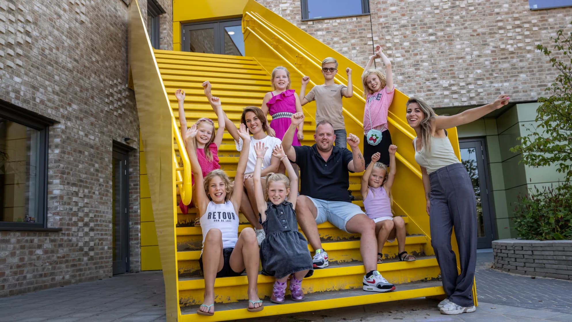 Kinderen zitten met pedagogisch medewerkers op een trap bij kinderopvang Kind&co ludens