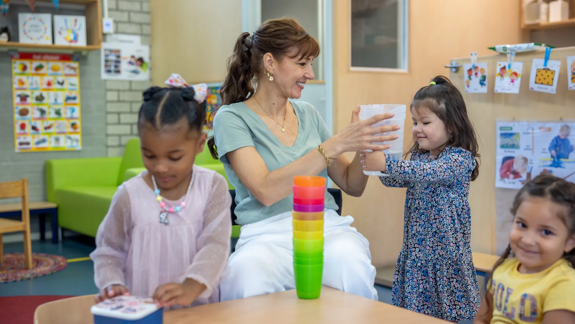 Kinderen schenken drinken in samen met pedagogisch medewerker bij kinderopvang Kind&co ludens