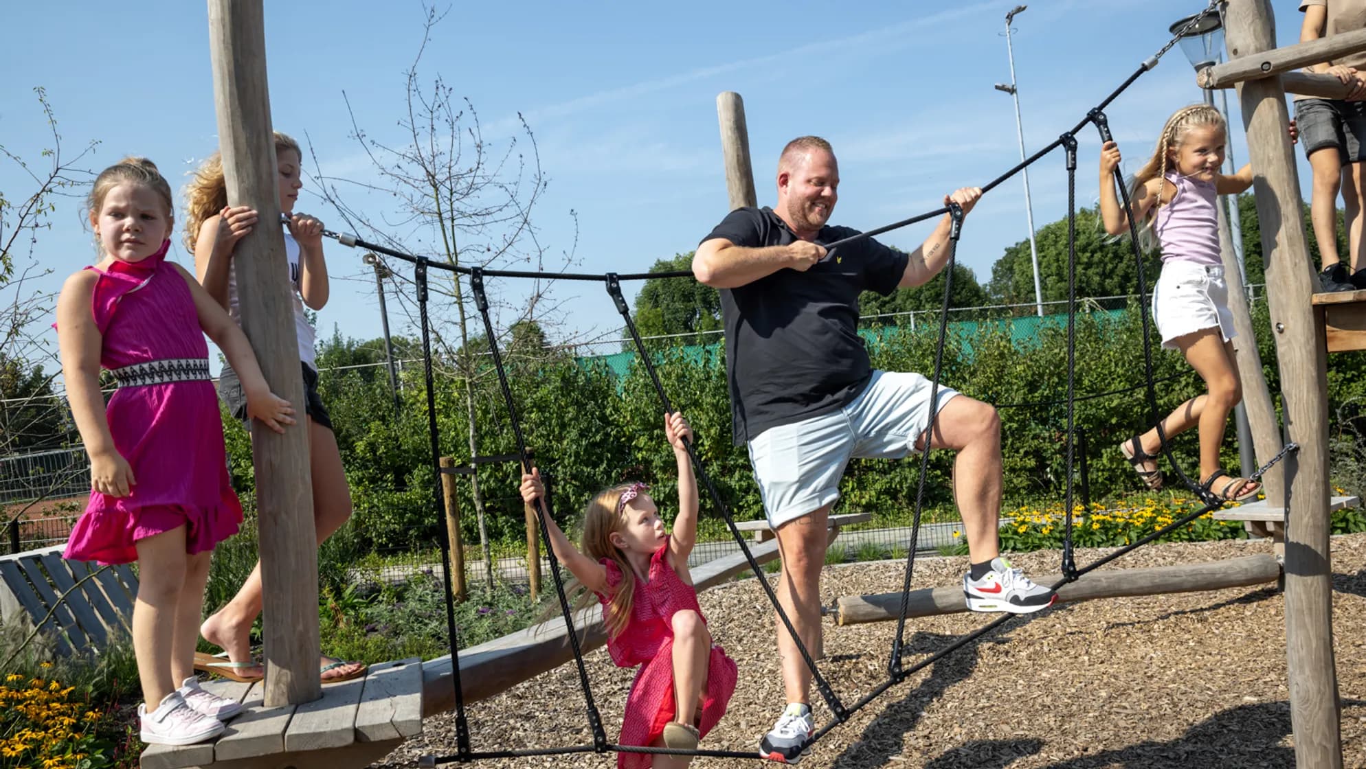 Kinderen spelen buiten met pedagogisch medewerker bij kinderopvang Kind&co ludens