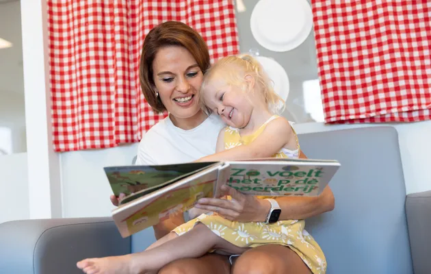 Pedagogisch medewerker leest kind voor bij kinderopvang Kind&co ludens