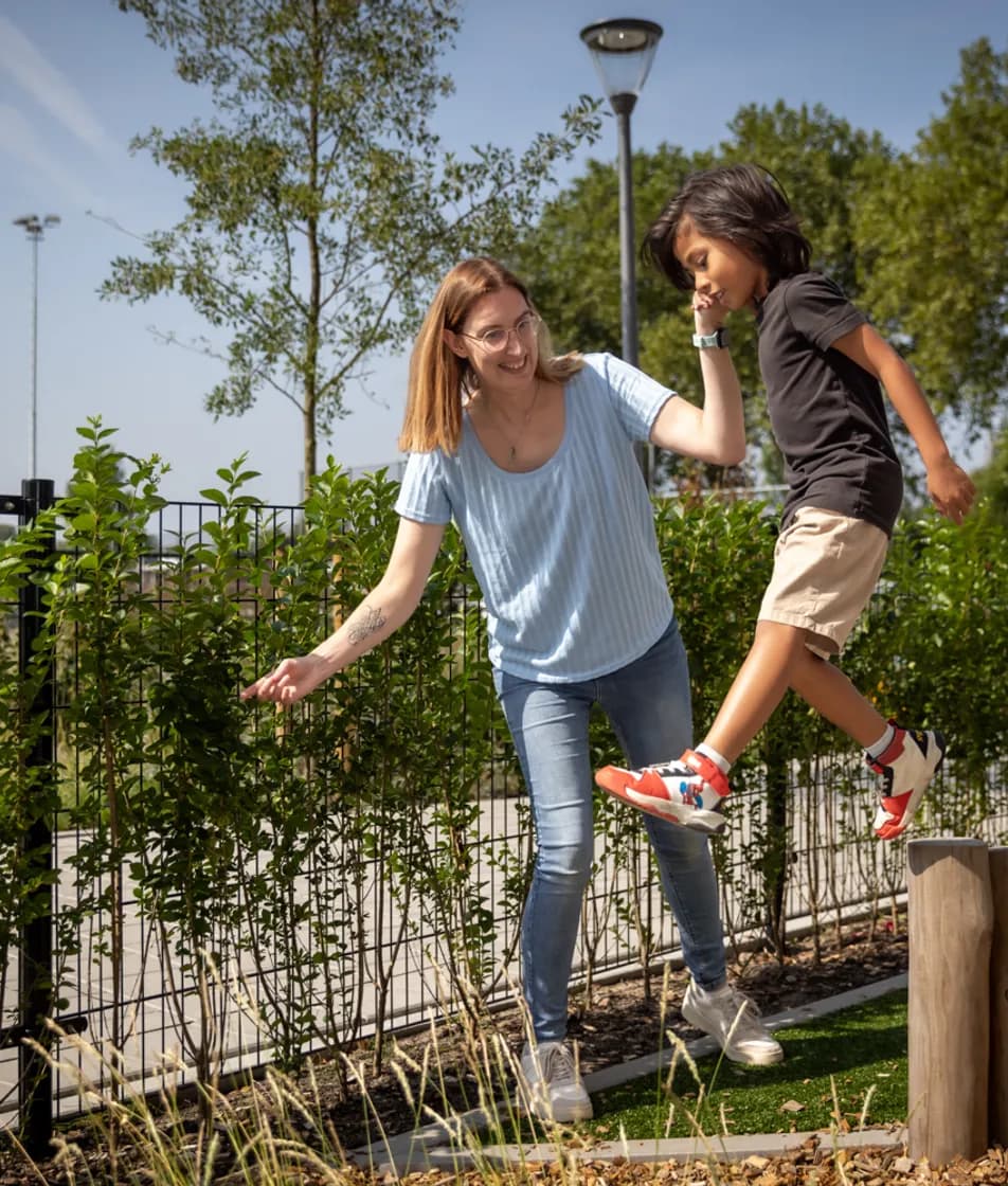 Kind speelt buiten met pedagogisch medewerker bij kinderopvang Kind&co ludens