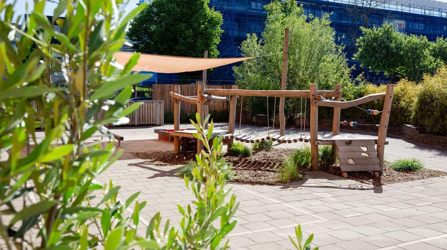 De buitenruimte met houten klim en klauter toestel bij peuteropvang de Olijfboom, kinderopvang Kind&co Ludens