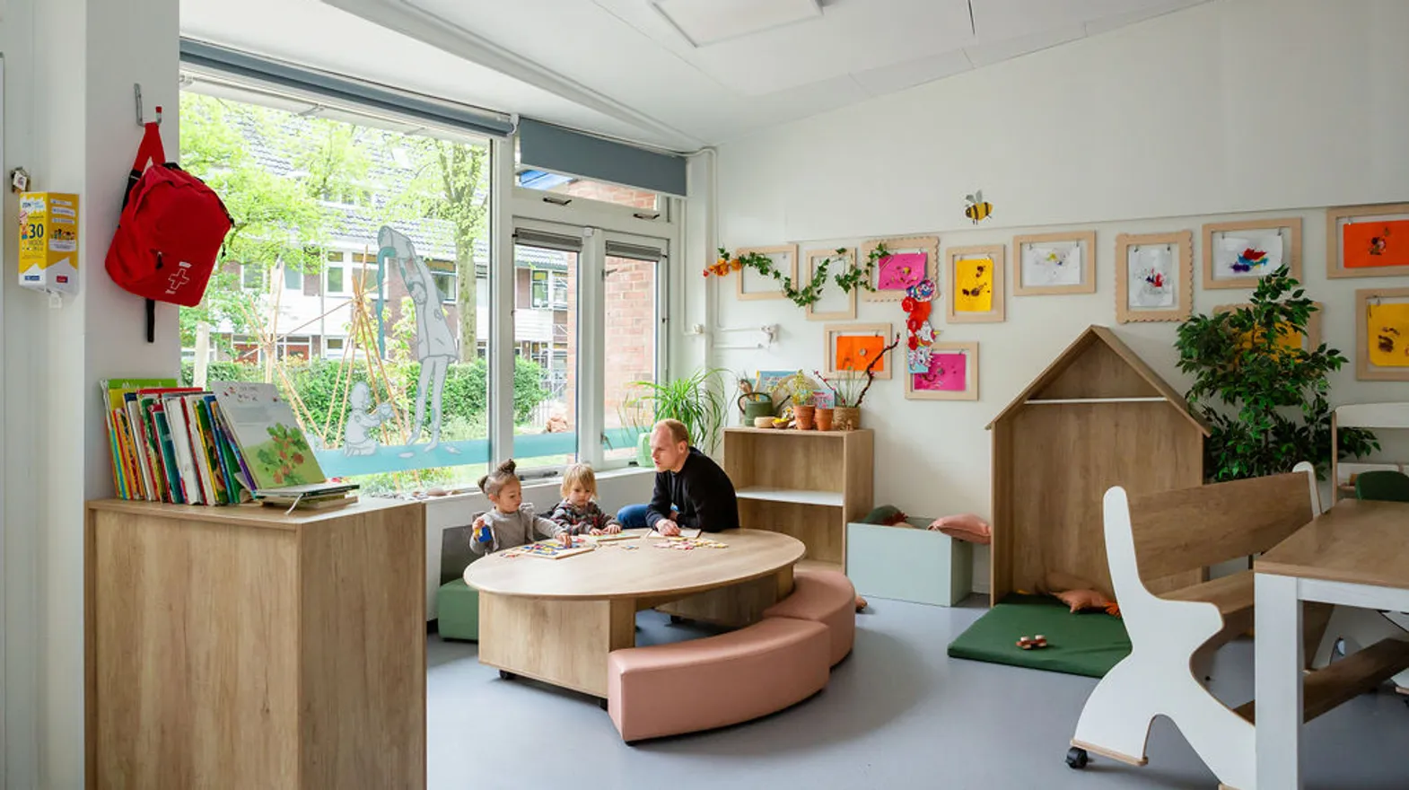 Kinderen spelen aan tafel een spel met pedagogisch medewerker bij kinderdagverblijf Nijntje, kinderopvang Kind&co ludens