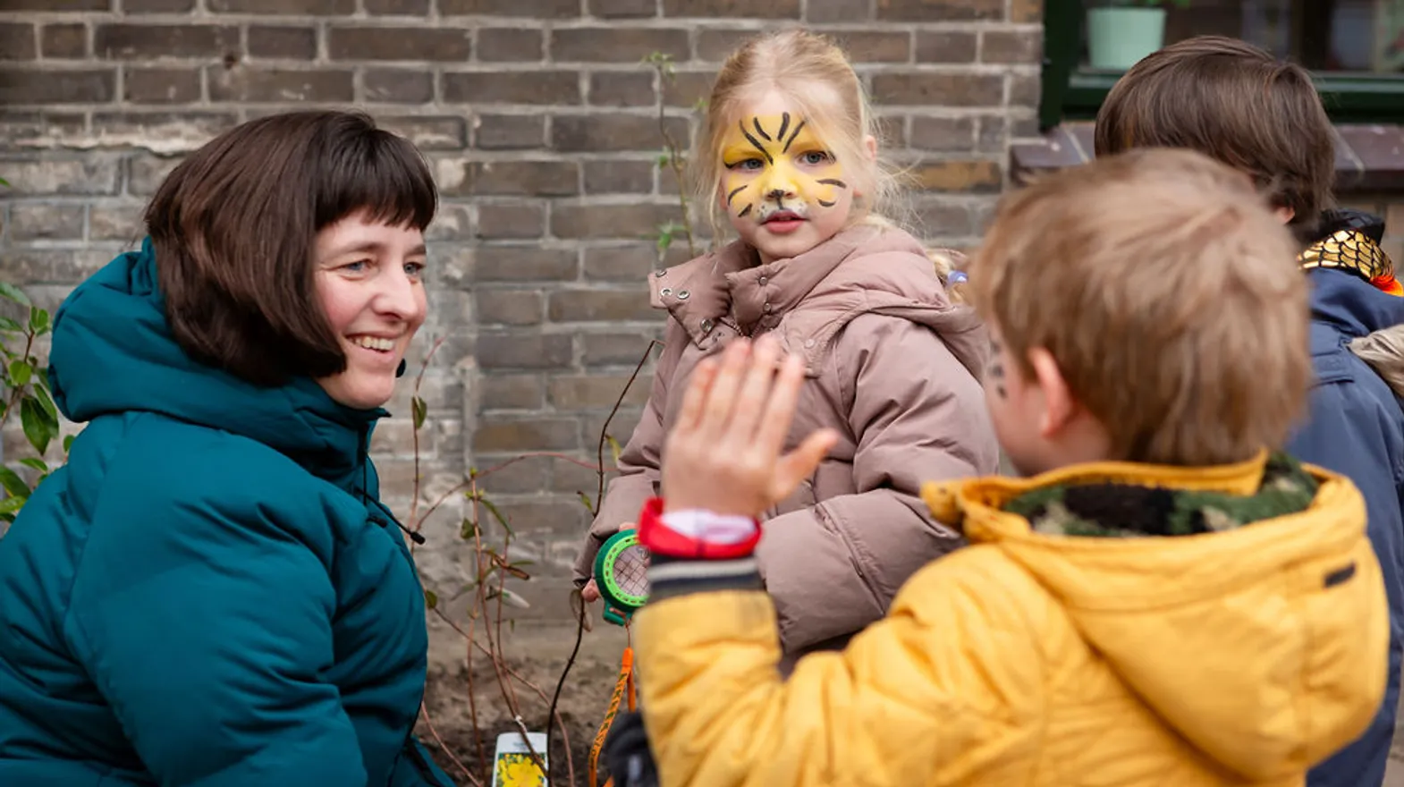 Pedagogisch medewerker lacht met kinderen buiten bij BSO Kikkersloot van Kind&co ludens
