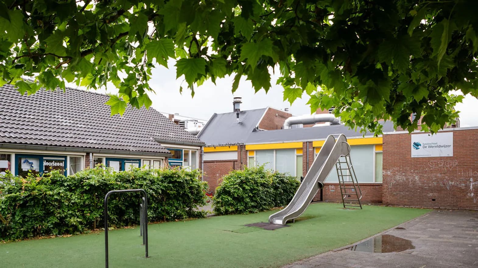 De tuin met glijbaan en klimtoestel van buitenschoolse opvang Wereldwijzer,  Kind&co Ludens