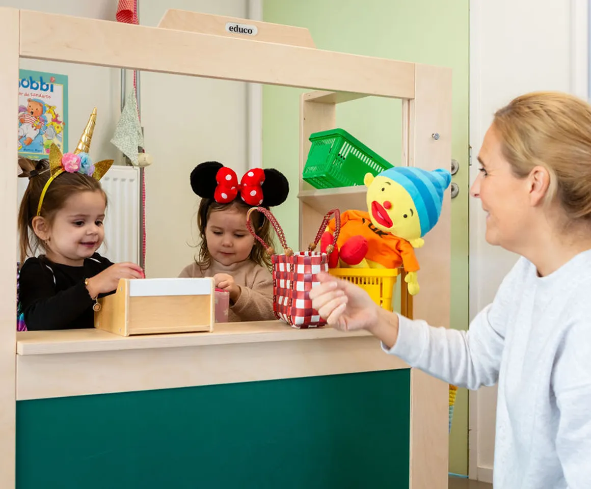 Pedagogisch medewerker speelt winkeltje met 2 kinderen bij peuteropvang Piraatje, kinderopvang Kind&co Ludens