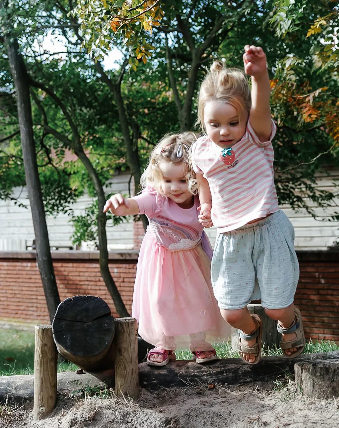 Kinderen springen samen van boomstam bij kinderopvang Kind&co ludens