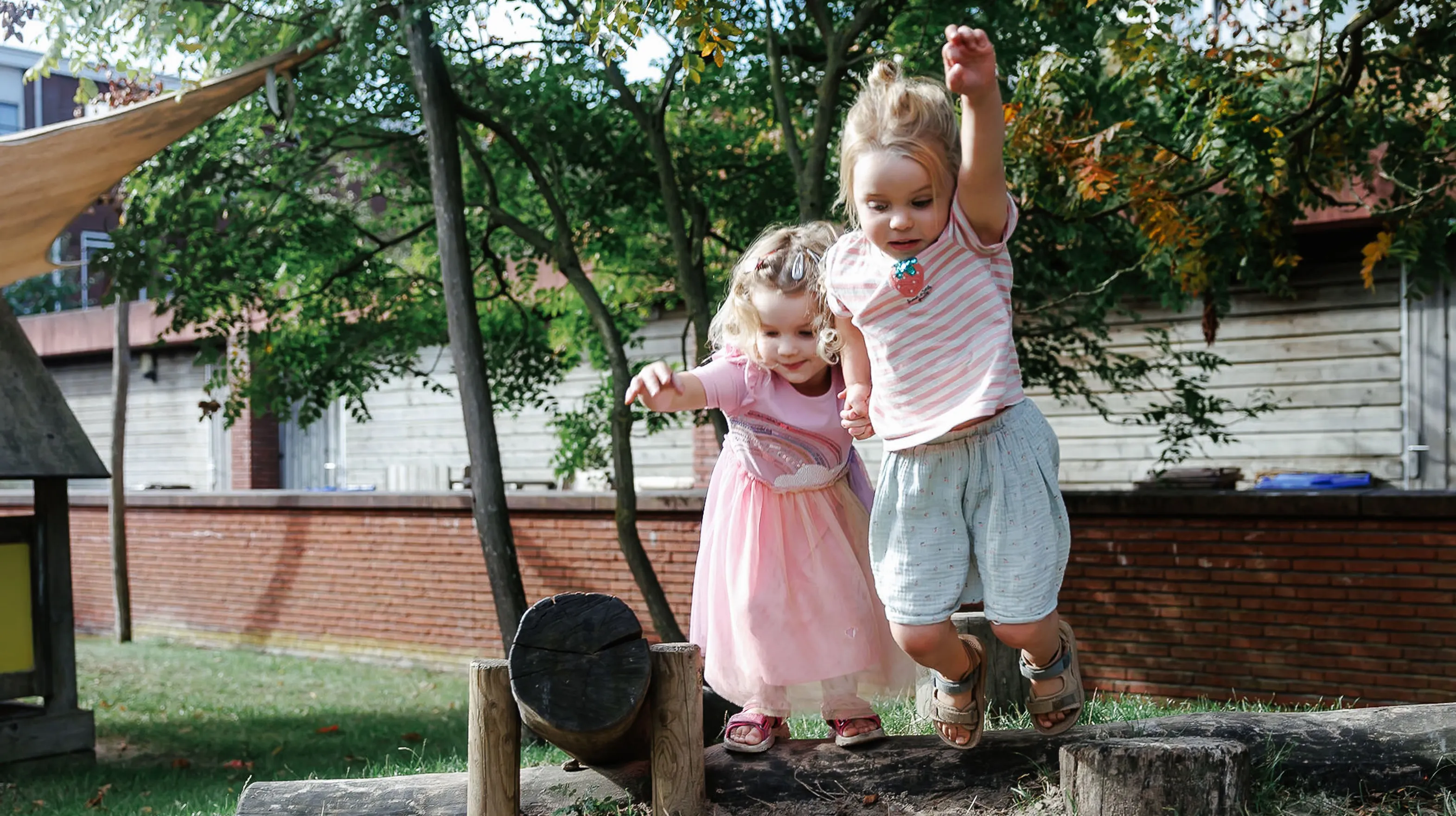 Kinderen springen samen van boomstam bij kinderopvang Kind&co ludens