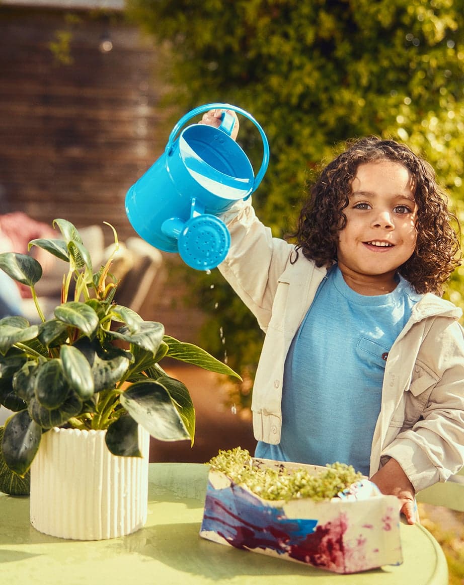 Kind geeft thuis zelfgemaakte moestuin in melkpak water