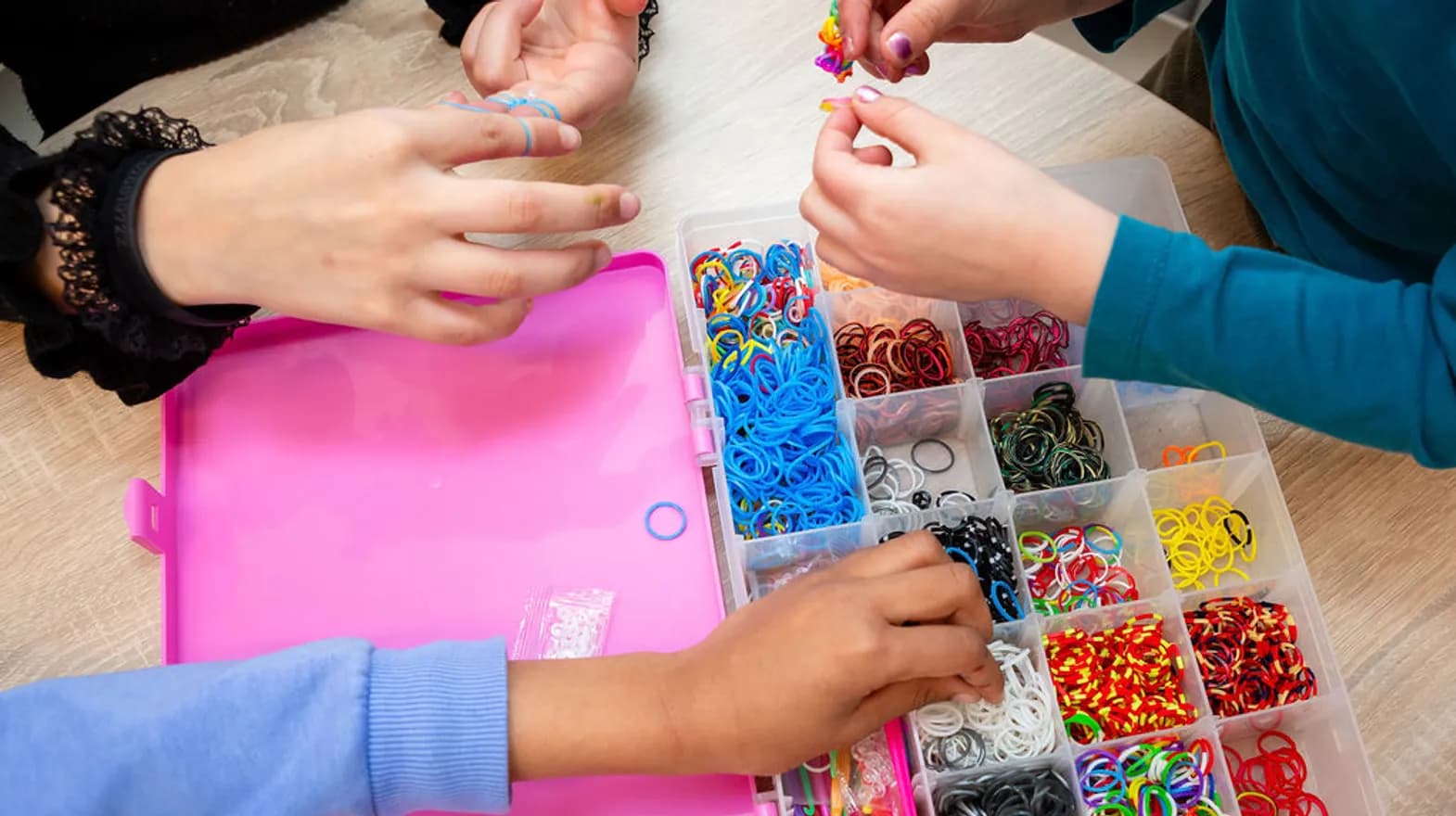 Kinderen maken loom armbanden samen aan tafel bij buitenschoolse opvang De Panter, kinderopvang Kind&co ludens