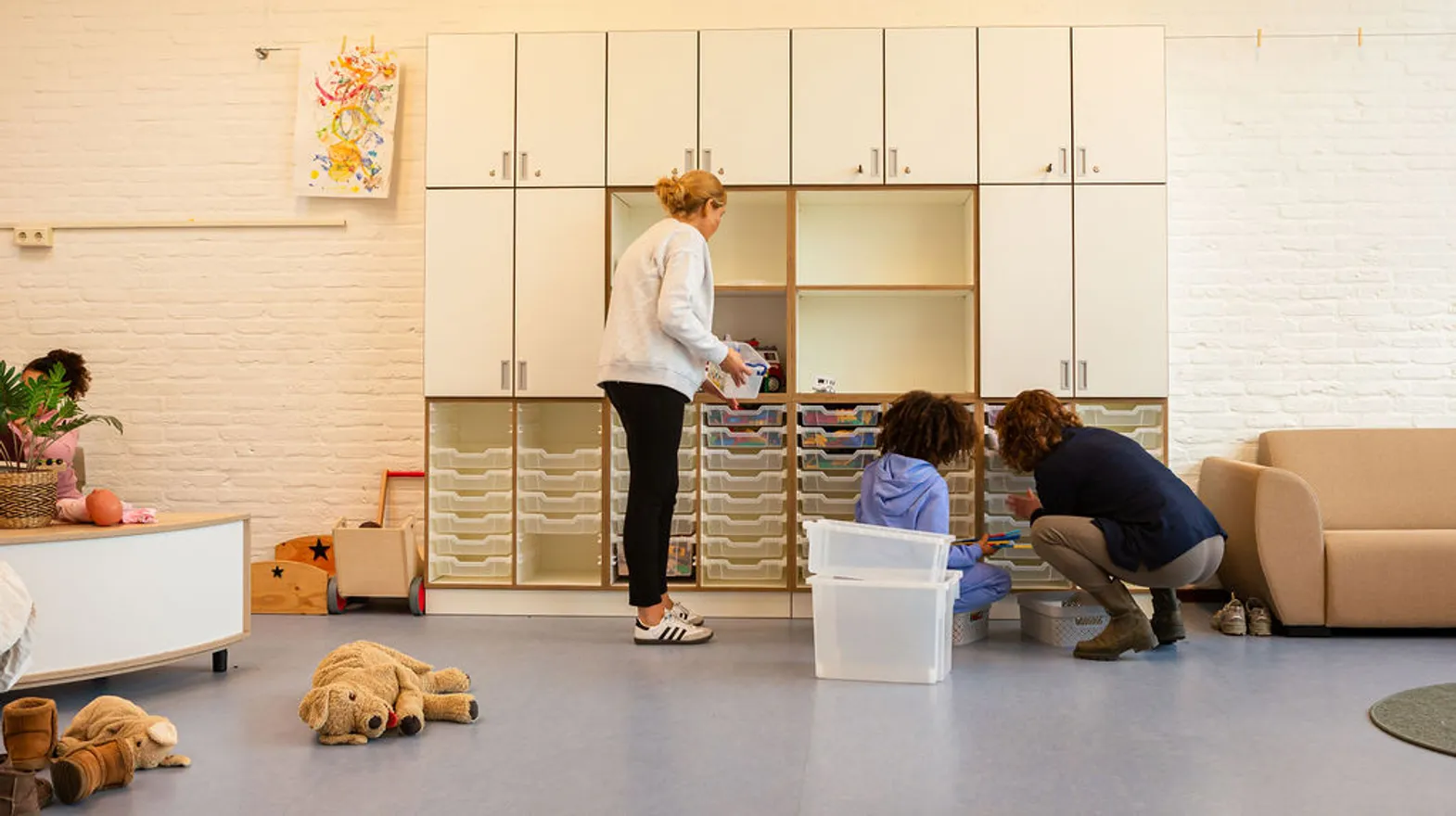 Kind pakt samen met pedagogisch medewerker speelgoed uit kast bij buitenschoolse opvang De Panter, kinderopvang Kind&co ludens