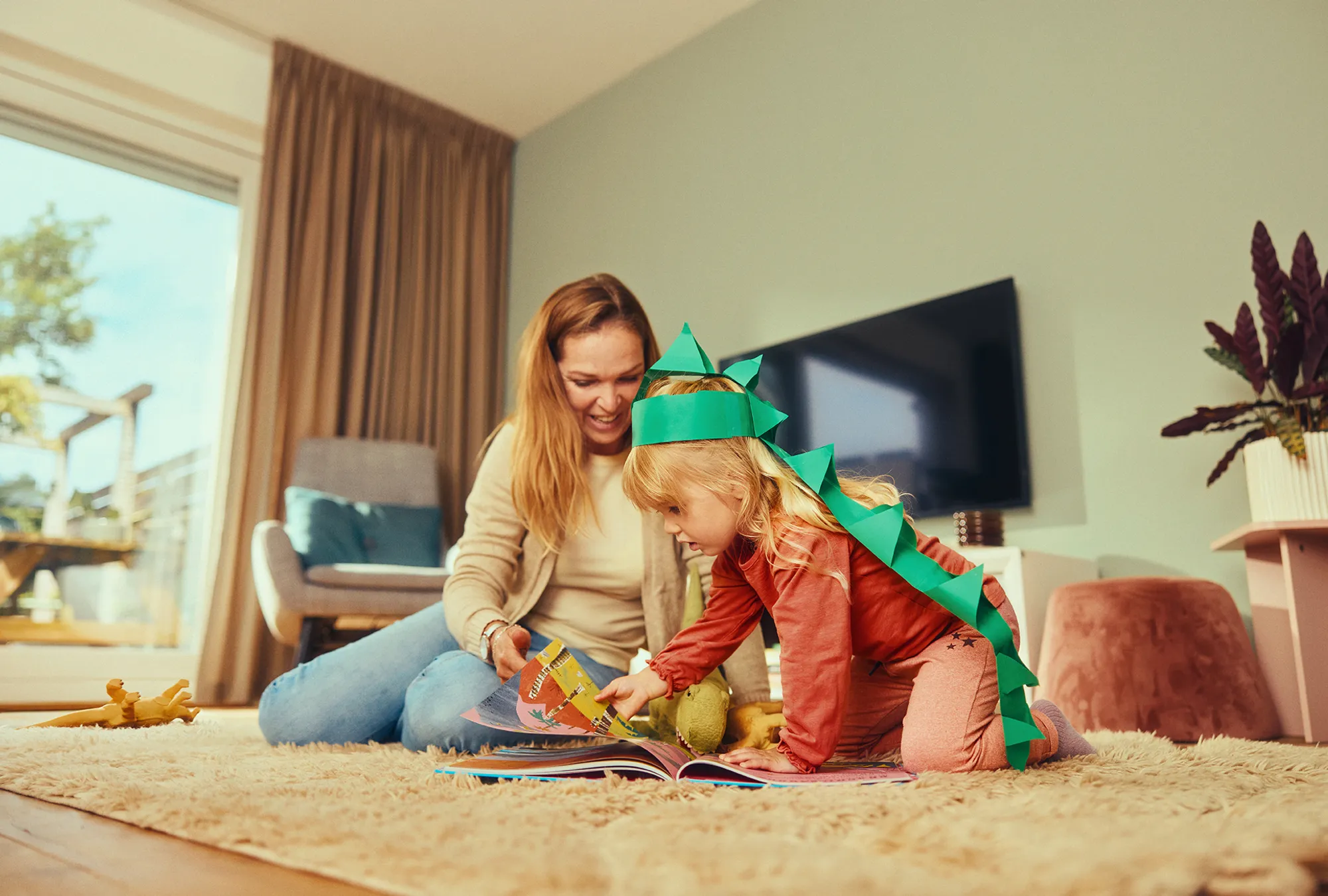 Kind met dinomuts leest met moeder in boek over dino's