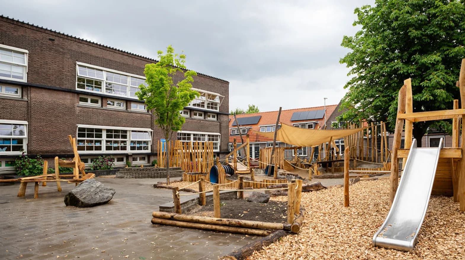 Het speelplein met houten klimtoestel in de tuin van buitenschoolse opvang Rijmgeheim, kinderopvang Kind&co Ludens
