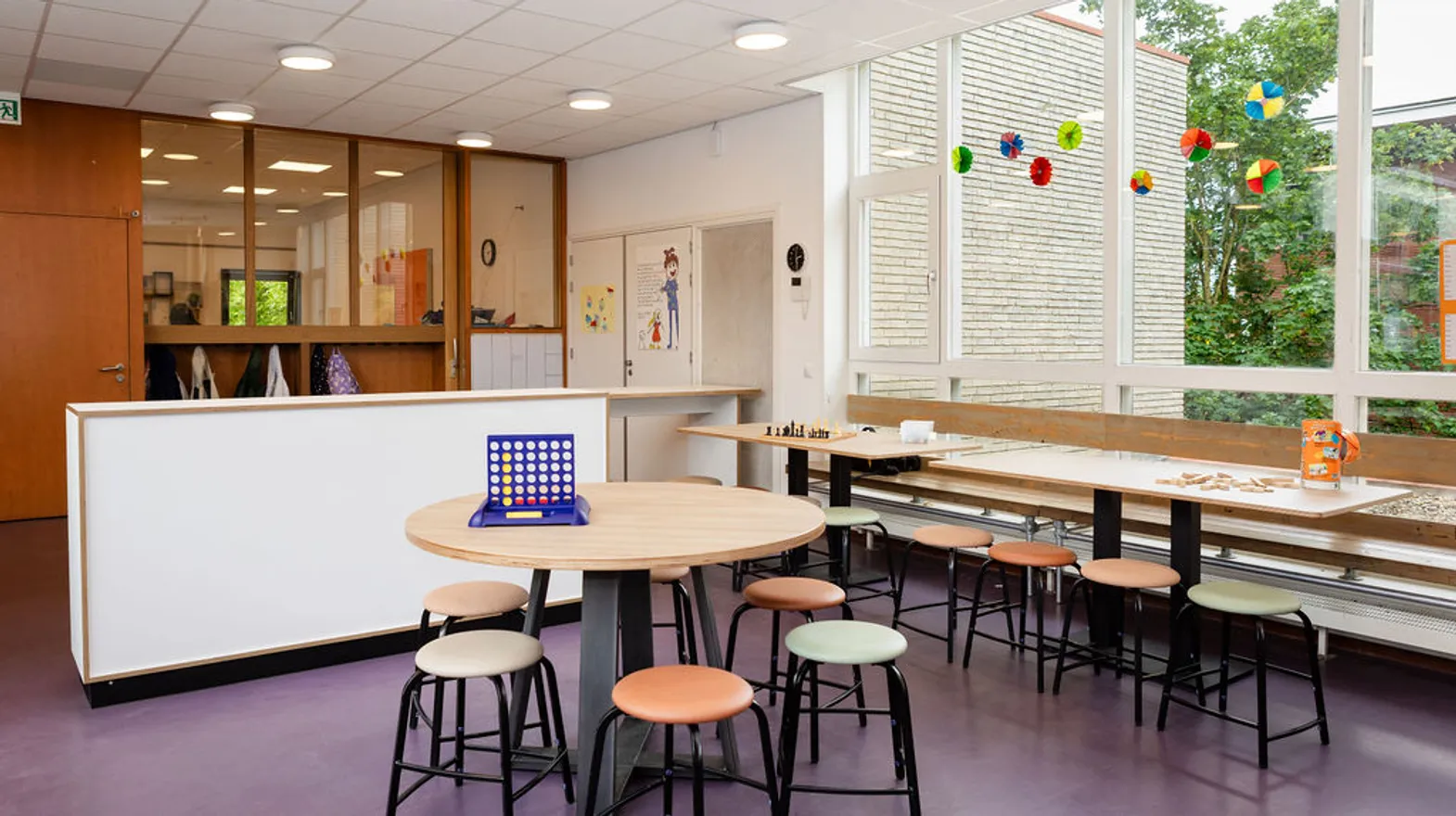 De hal met kapstokken en zitjes om aan te spelen bij buitenschoolse opvang Troubadour bij kinderopvang Kind&co Ludens