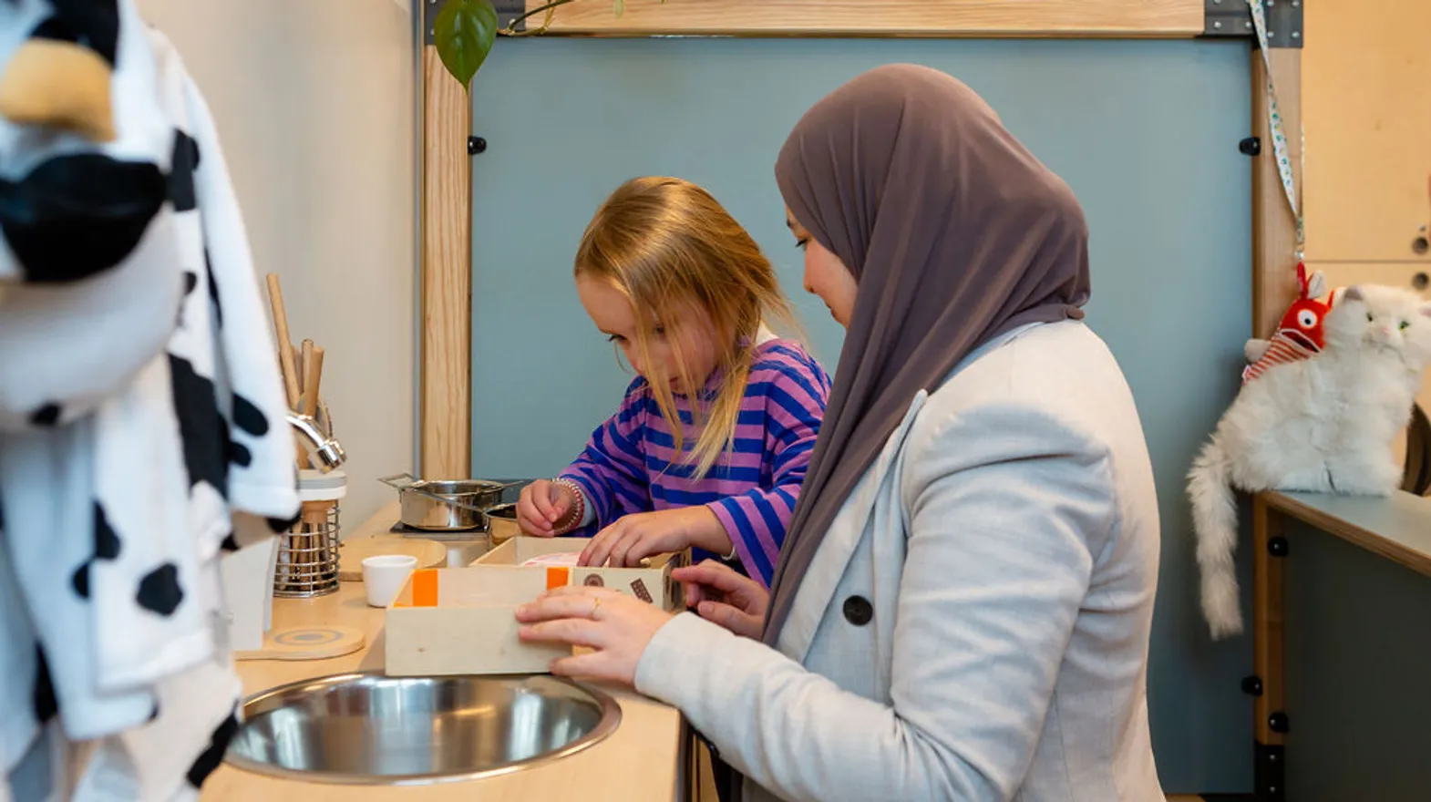 Pedagogisch medewerker speelt in het keukentje met een kind bij BSO Kikkersloot van Kind&co ludens