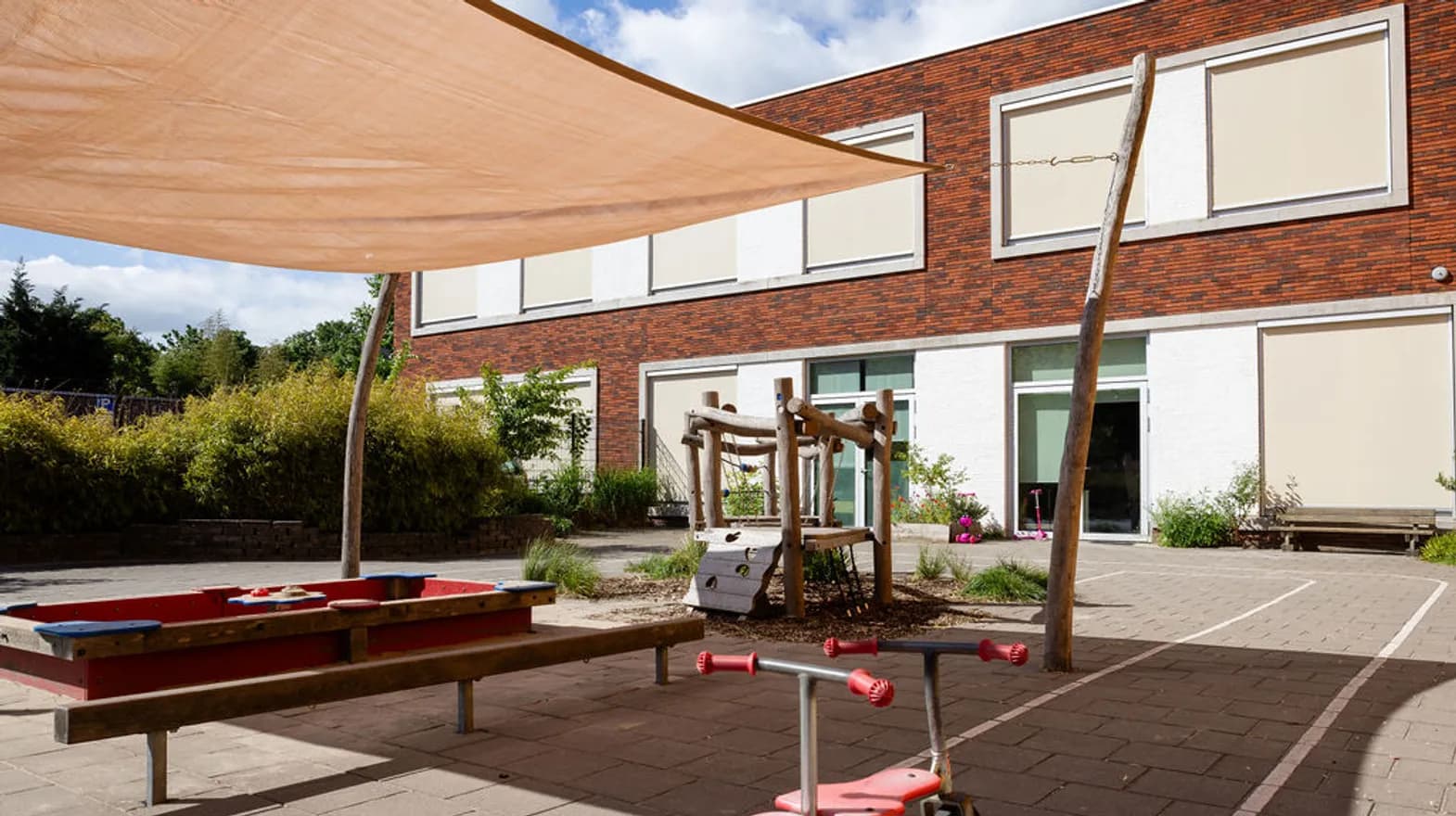 De buitenruimte zandbak en klimtoestel bij peuteropvang de Olijfboom, kinderopvang Kind&co Ludens