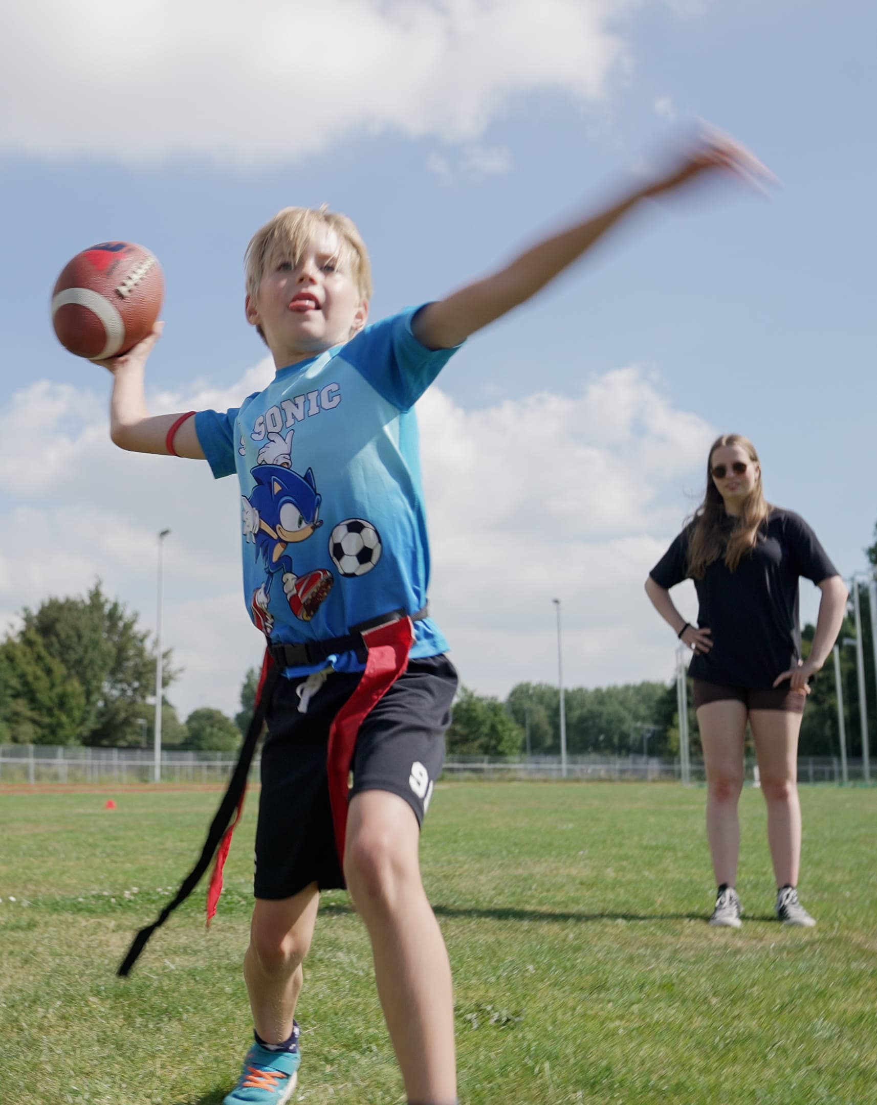 Kind gooit rugbybal op een veld tijdens sporten op de BSO