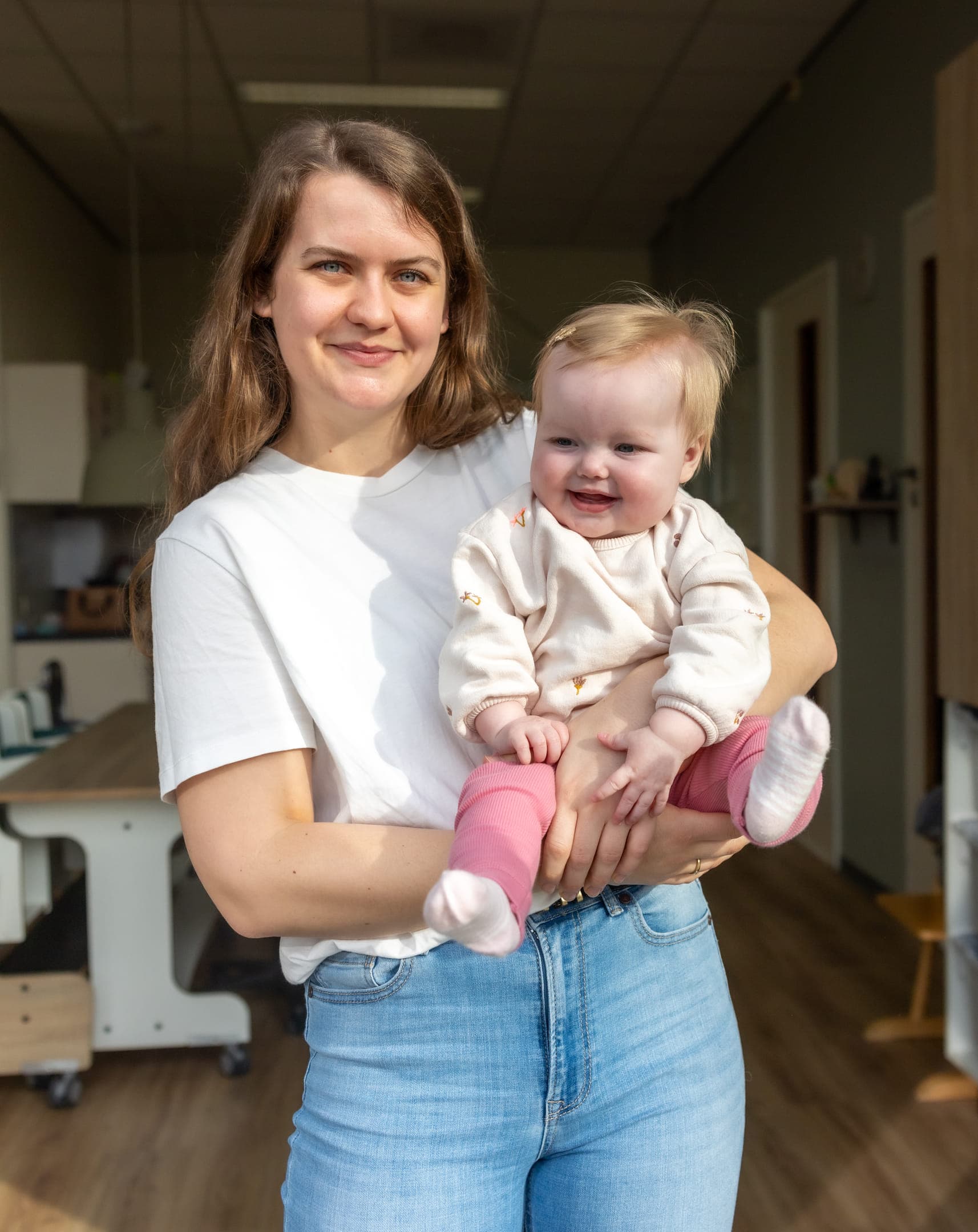 Blije baby in handen van een pedagogisch medewerker bij kinderopvang Kind&co ludens