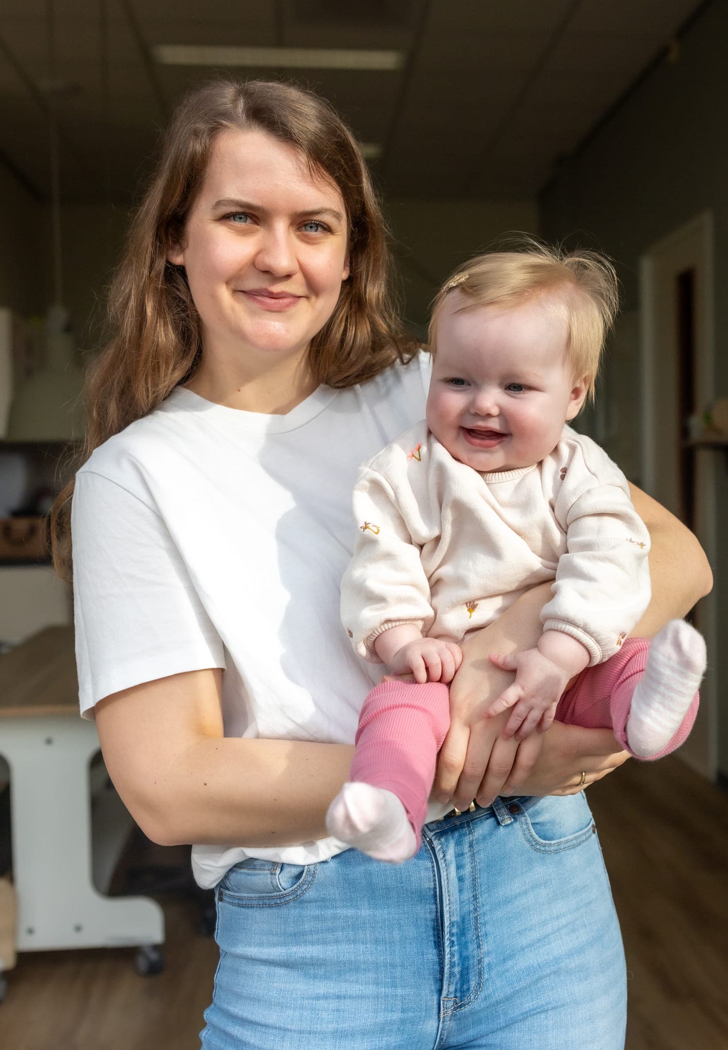 Blije baby in handen van een pedagogisch medewerker bij kinderopvang Kind&co ludens