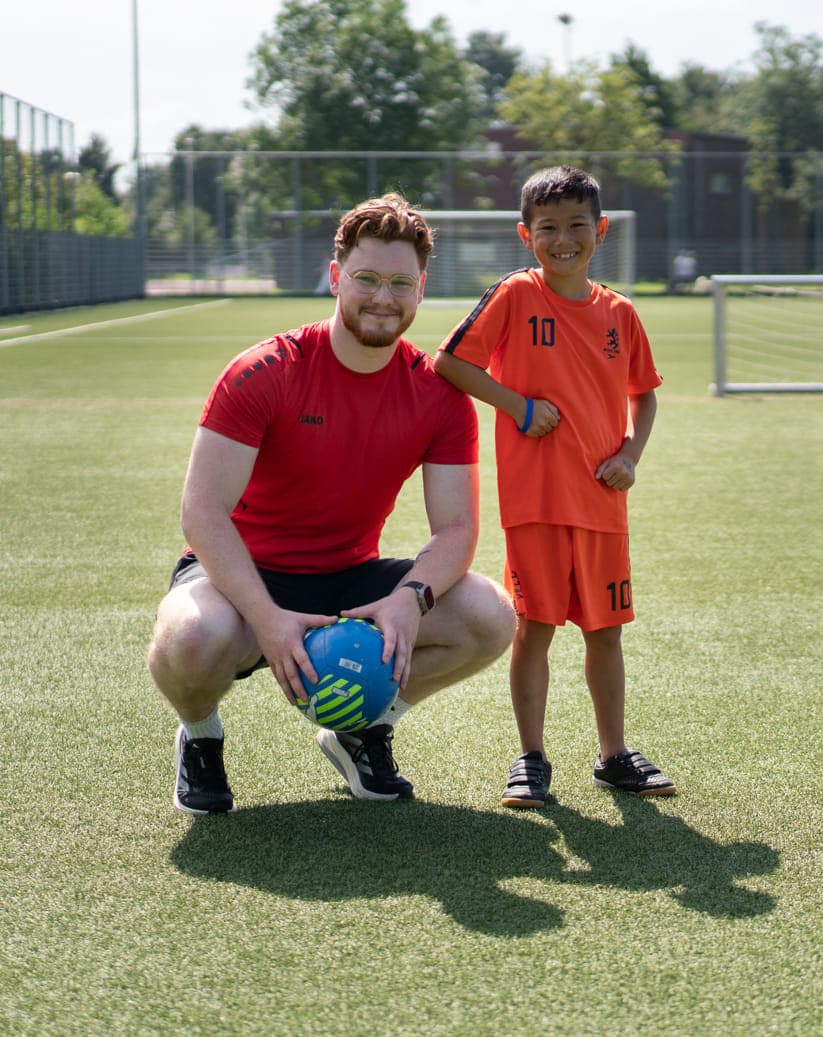 Collega met kind op een sportveld op de BSO