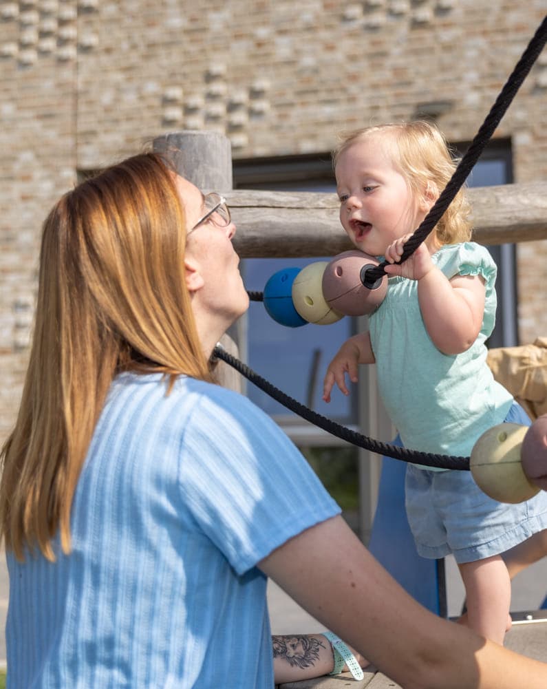 Kinderen klimmen buiten met pedagogisch medewerker bij kinderopvang Kind&co ludens