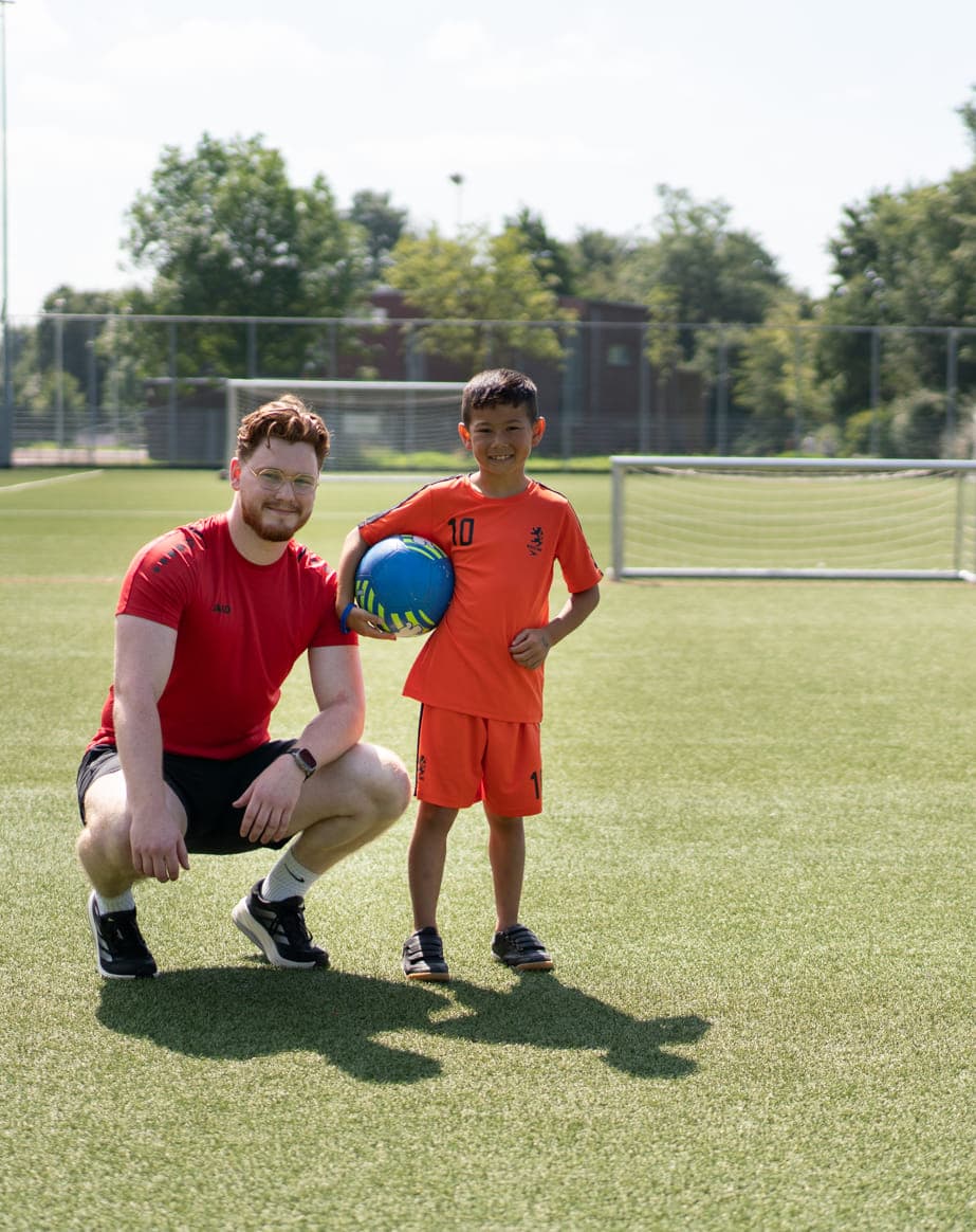 Collega en kind op een sportveld op de BSO