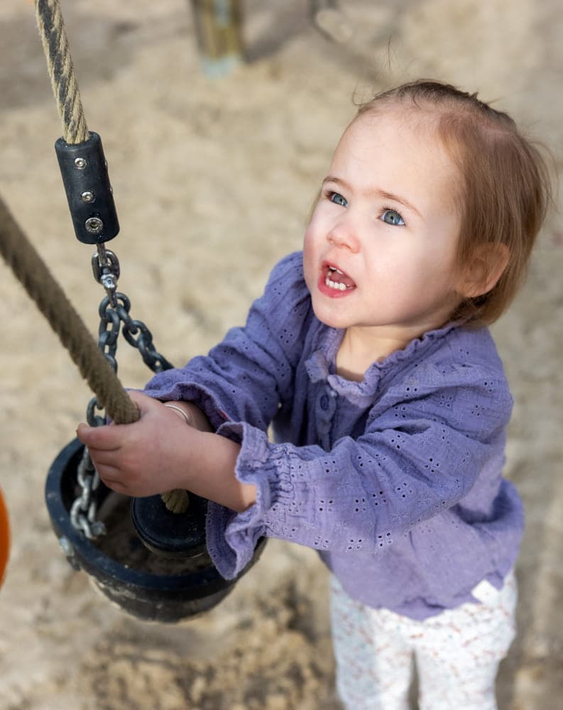 Kind speelt buiten met een speeltoestel bij kinderopvang Kind&co ludens