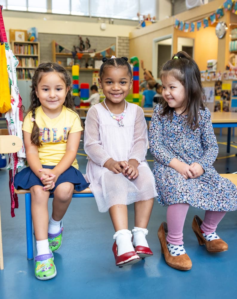 Kinderen zitten samen op een bankje bij kinderopvang Kind&co ludens
