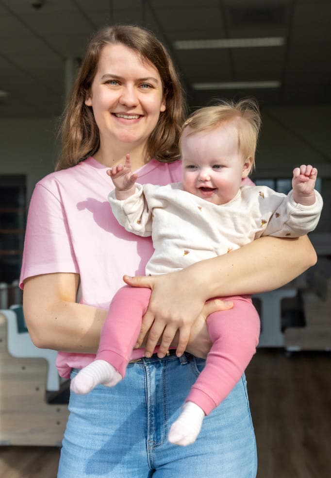 Blij kind op de armen bij een pedagogisch medewerker bij kinderopvang Kind&co ludens