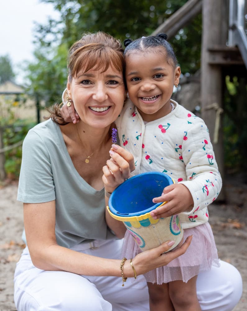 Kind speelt buiten met pedagogisch medewerker bij kinderopvang Kind&co ludens