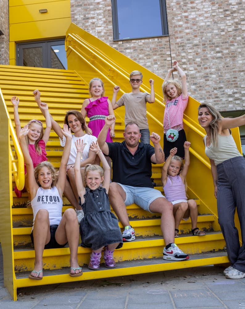 Kinderen zitten met pedagogisch medewerkers op een trap bij kinderopvang Kind&co ludens