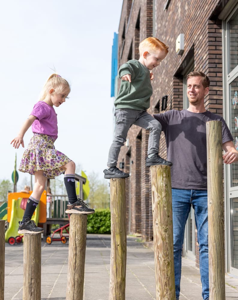 Kinderen spelen buiten met pedagogisch medewerkers bij kinderopvang Kind&co ludens