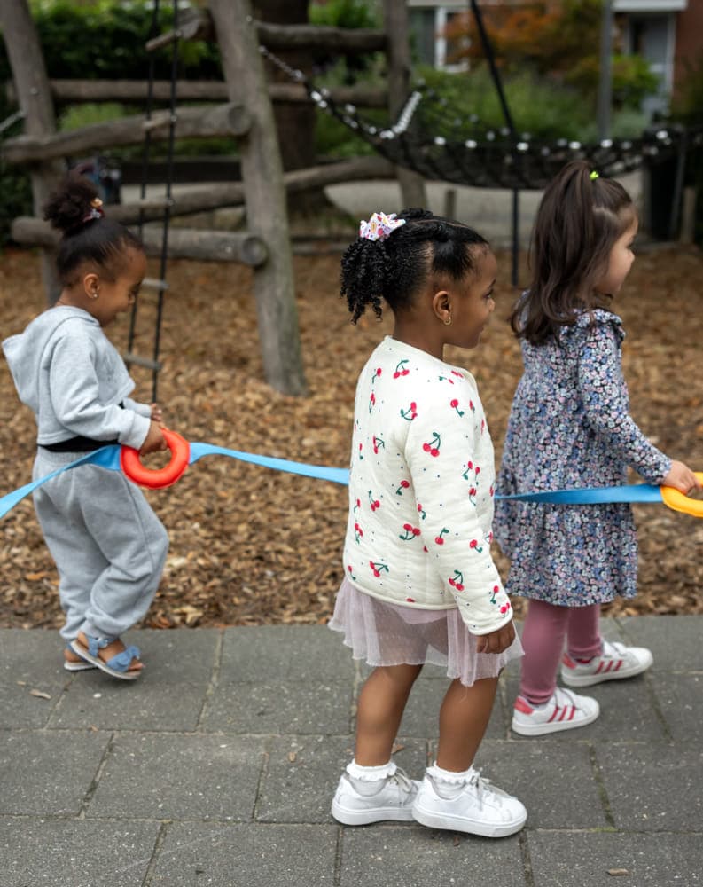 Kinderen wandelen aan evacuatiekoord met pedagogisch medewerker bij kinderopvang Kind&co ludens