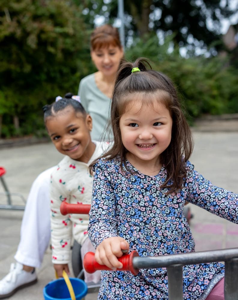 Kinderen spelen buiten met pedagogisch medewerker bij kinderopvang Kind&co ludens