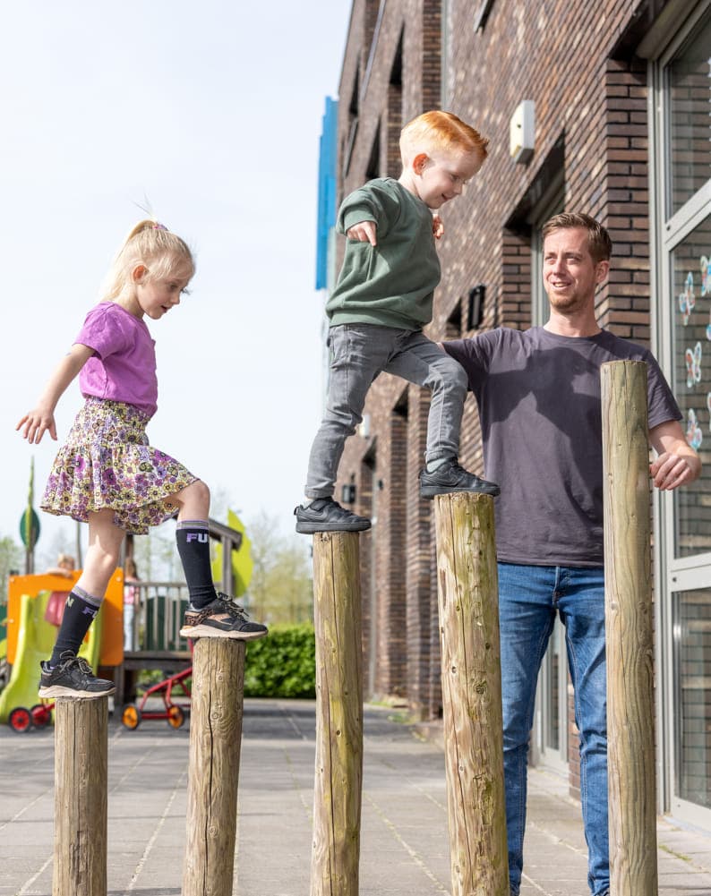 Kinderen spelen buiten met pedagogisch medewerkers bij kinderopvang Kind&co ludens