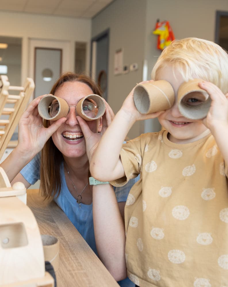 Kind speelt met wc rollen met pedagogisch medewerker bij kinderopvang Kind&co ludens