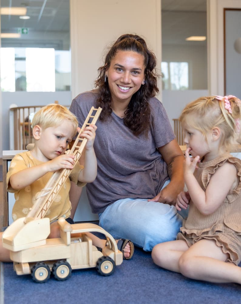 Kinderen spelen samen met pedagogisch medewerker bij kinderopvang Kind&co ludens