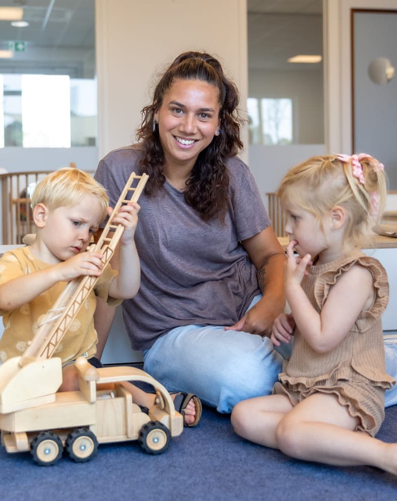 Kinderen spelen samen met pedagogisch medewerker bij kinderopvang Kind&co ludens
