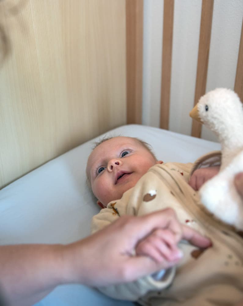 Baby kijkt liefdevol naar pedagogisch medewerker bij kinderopvang Kind&co ludens