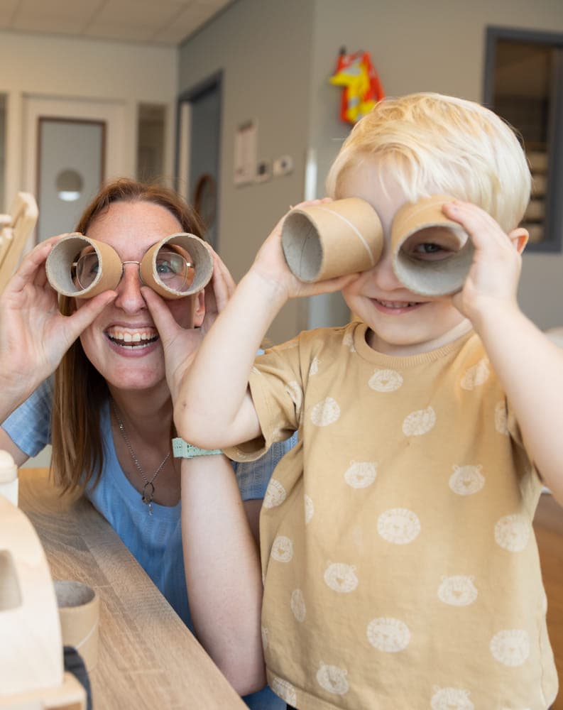 Kind speelt met wc rollen met pedagogisch medewerker bij kinderopvang Kind&co ludens