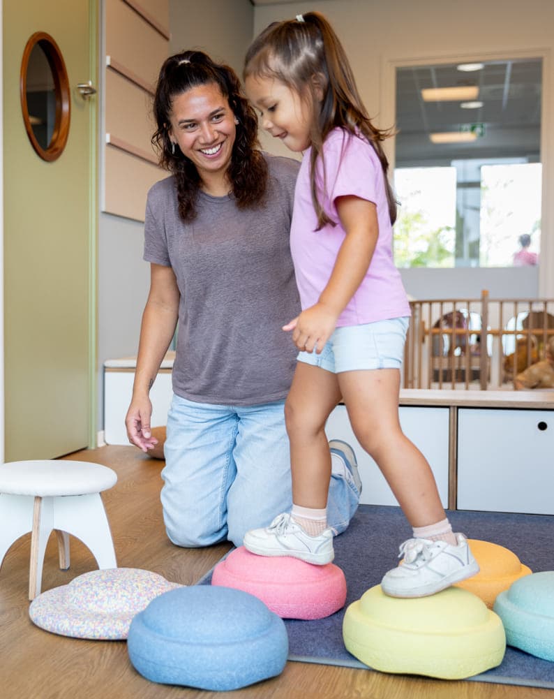 Kinderen spelen samen met pedagogisch medewerker met stapelstenen bij kinderopvang Kind&co ludens