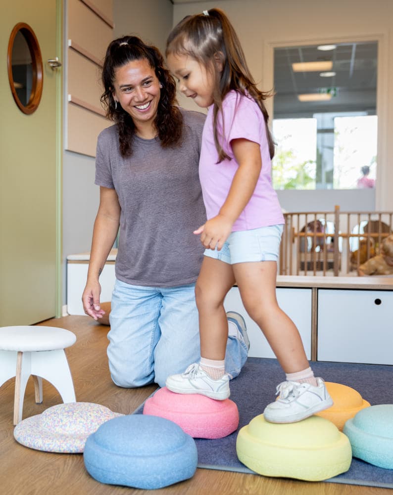 Kinderen spelen samen met pedagogisch medewerker met stapelstenen bij kinderopvang Kind&co ludens