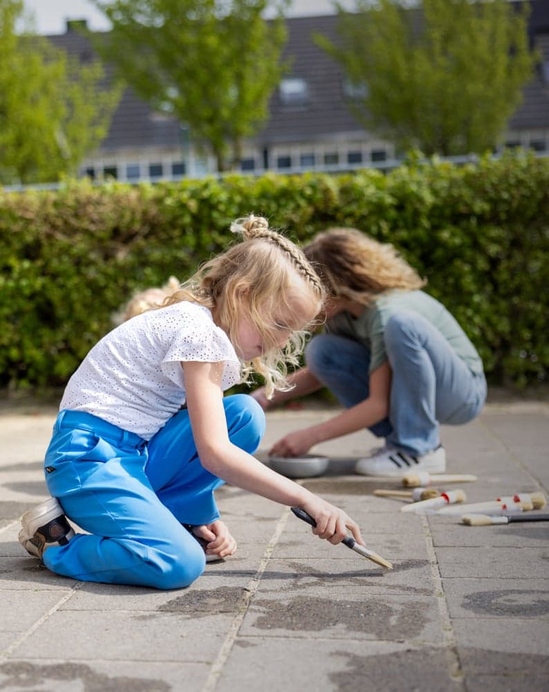Kinderen spelen buiten op de grond bij kinderopvang Kind&co ludens