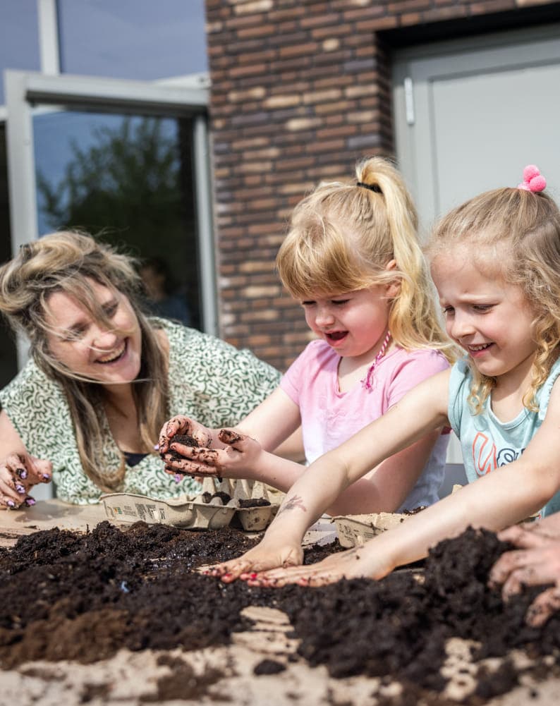 Kinderen tuinieren met pedagogisch medewerker bij kinderopvang Kind&co ludens