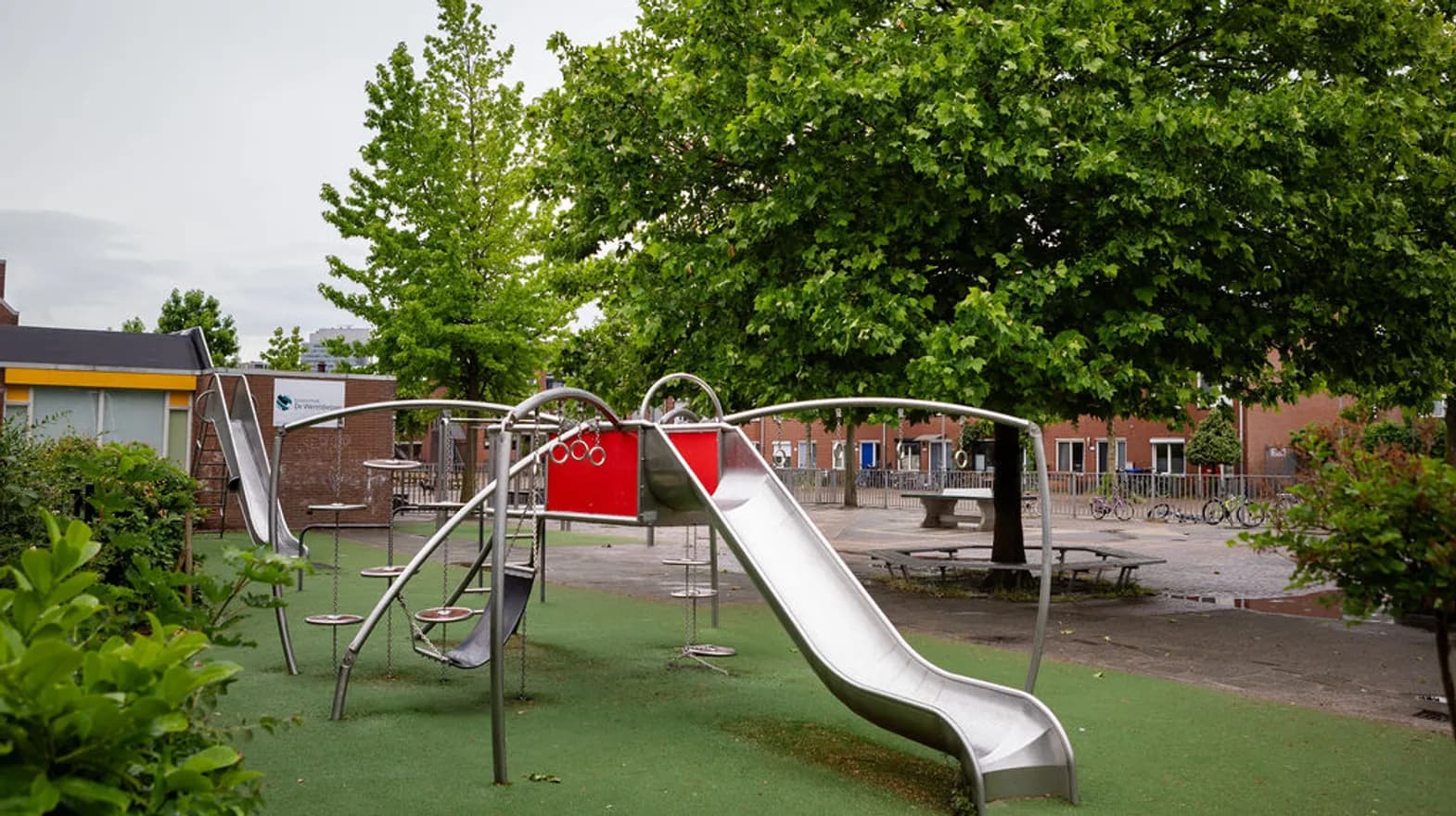 De tuin met glijbaan en klimtoestel van peuteropvang Wereldwijzer,  Kind&co Ludens
