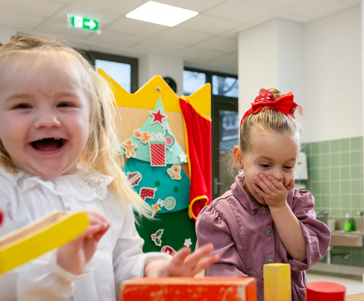 Kinderen van de peutergroep lachen en spelen samen bij kinderopvang Kind&co ludens