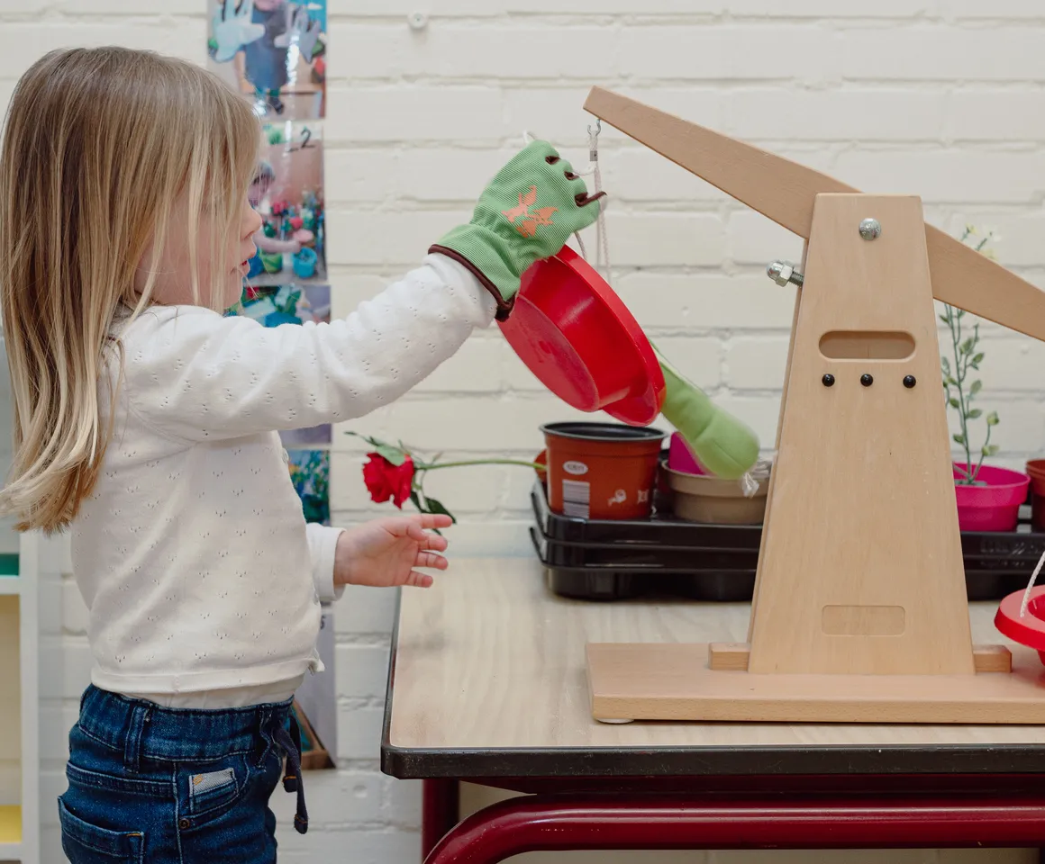 Een kind van de peutergroep speelt met een weegschaal bij kinderopvang Kind&co ludens